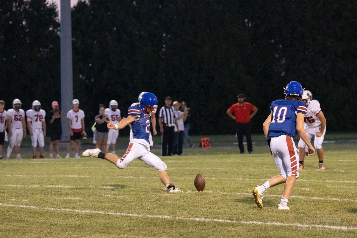 A football player with the number 10 on his jersey is kicking a ball.