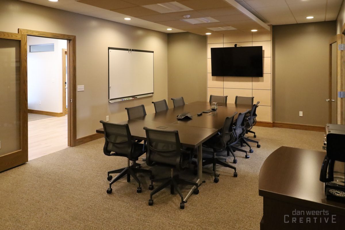 A conference room with a long table and chairs and a flat screen tv.