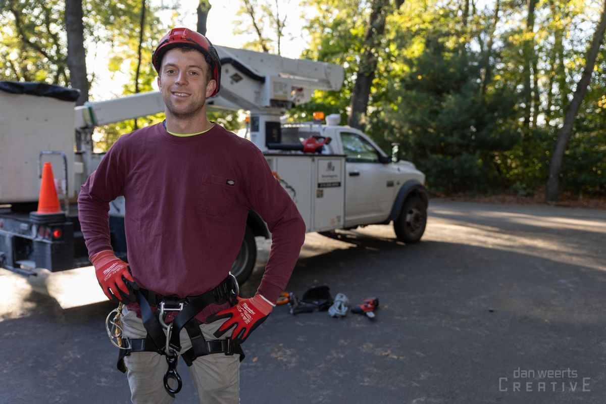A man wearing a hard hat and gloves is standing in front of a truck.