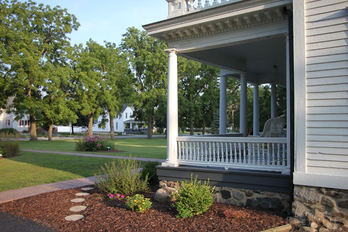 A white house with a porch and trees in the background