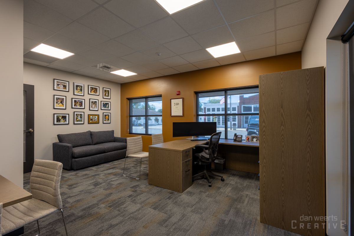 A living room with a couch , desk , chairs and a computer.