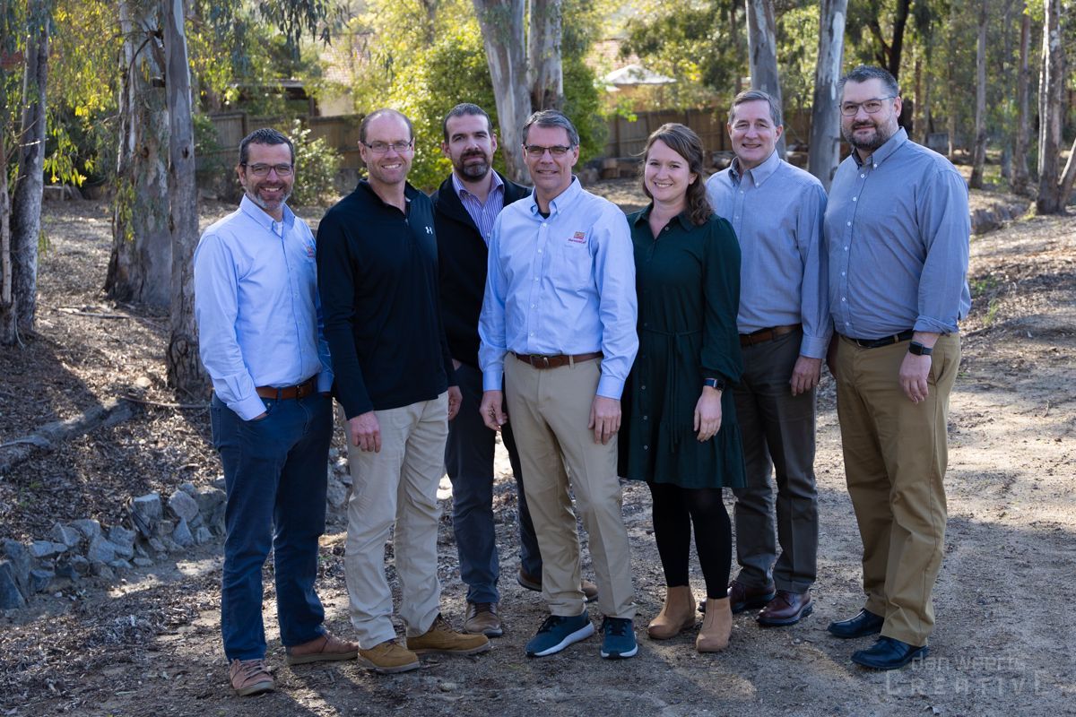 A group of people are posing for a picture in the woods.