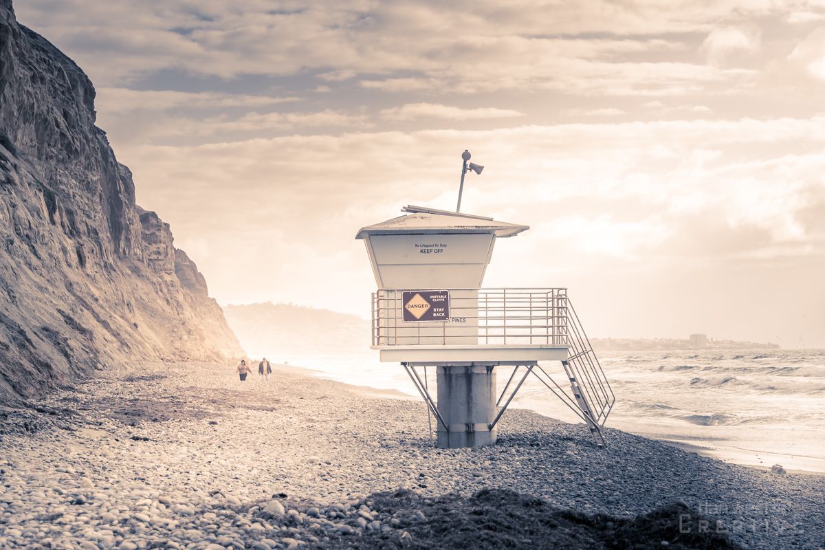 A lifeguard tower on a rocky beach next to the ocean.