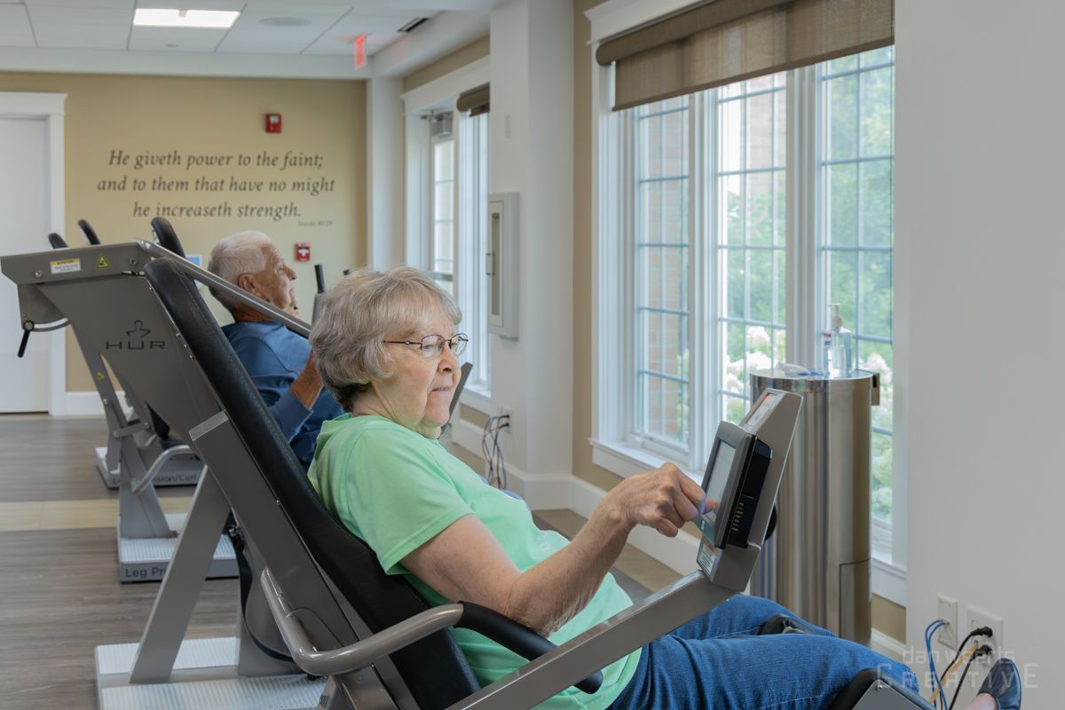 A man and a woman are sitting on exercise bikes in a gym.