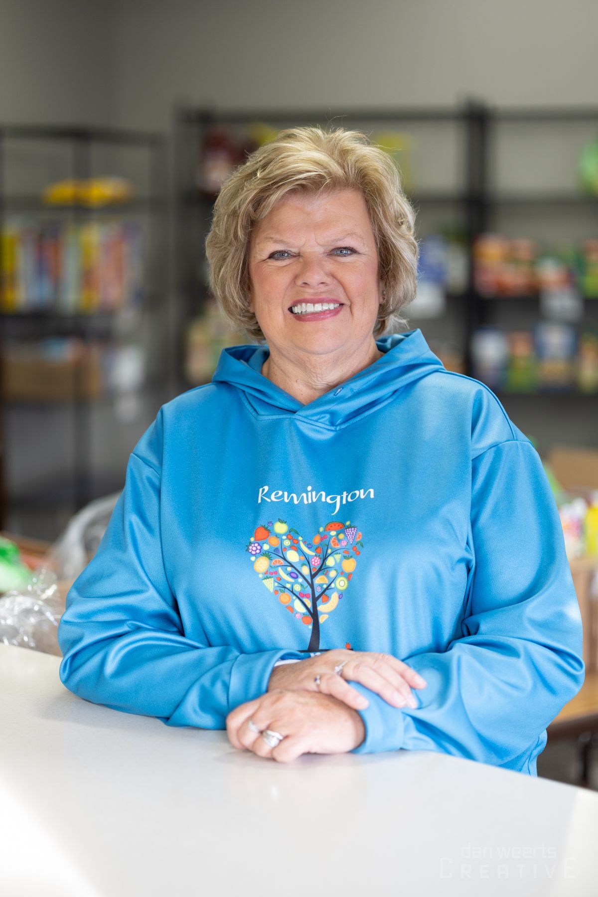 A woman in a blue hoodie is sitting at a counter in a store.
