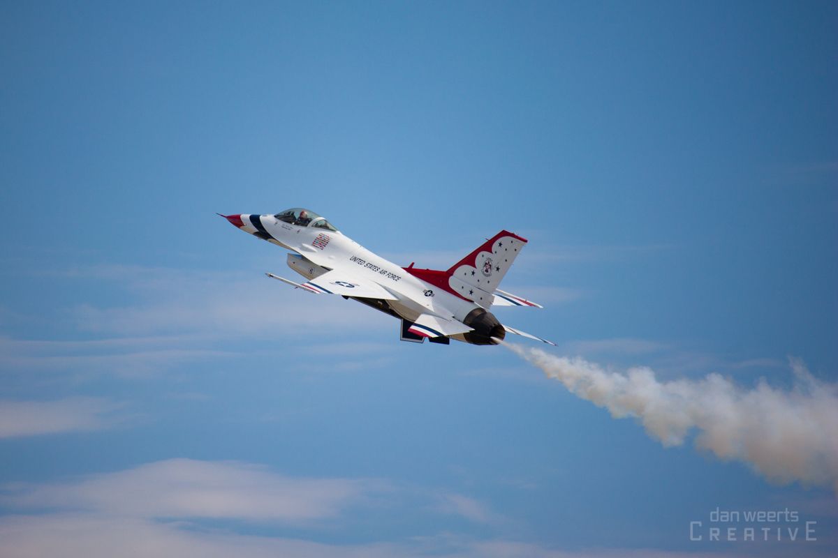 A fighter jet is flying through a blue sky with smoke coming out of it.