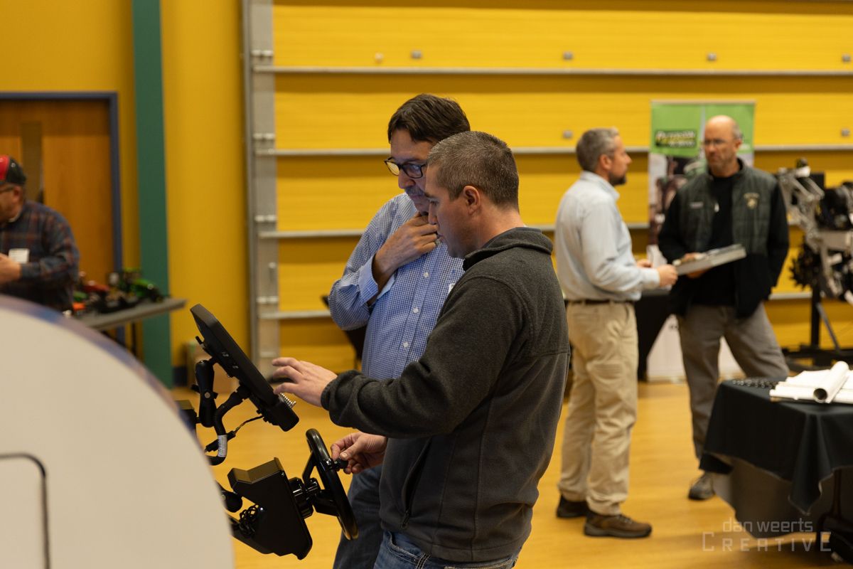 A group of men are standing in a room looking at a computer screen.