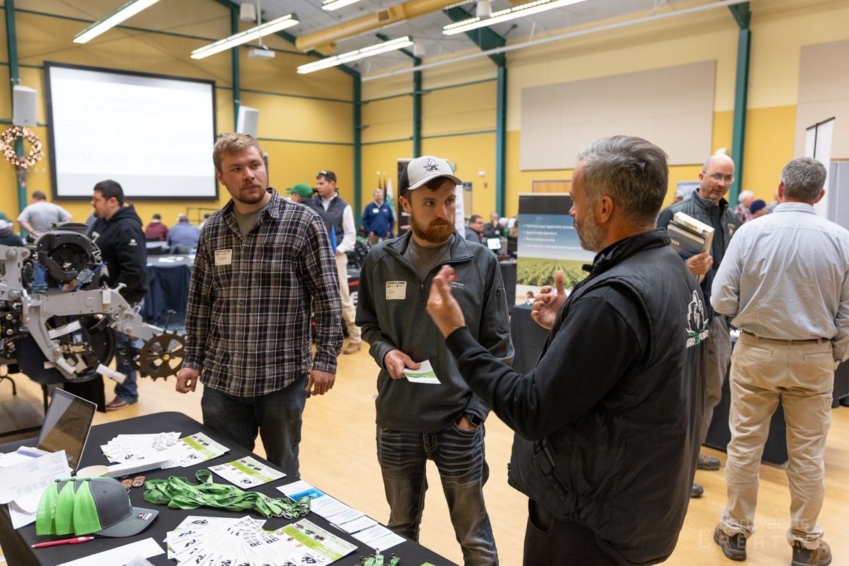 A group of men are standing around a table talking to each other.