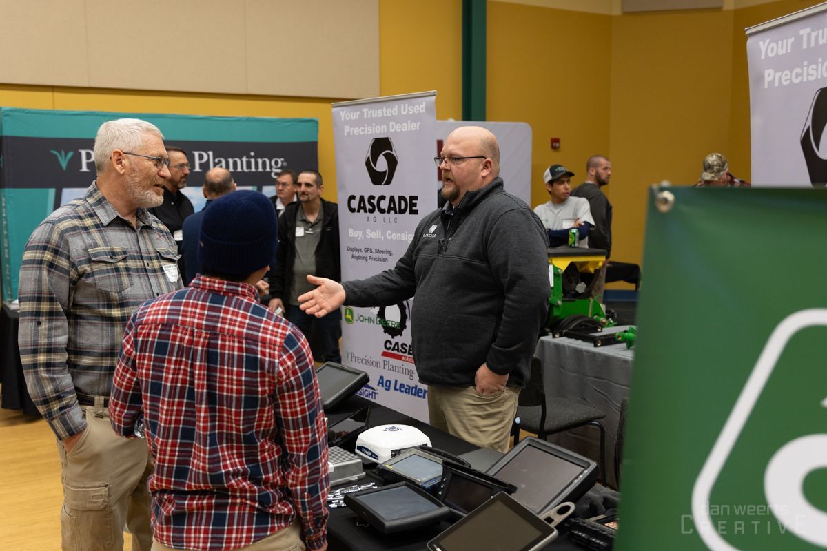 A group of men are standing around a table at a trade show.