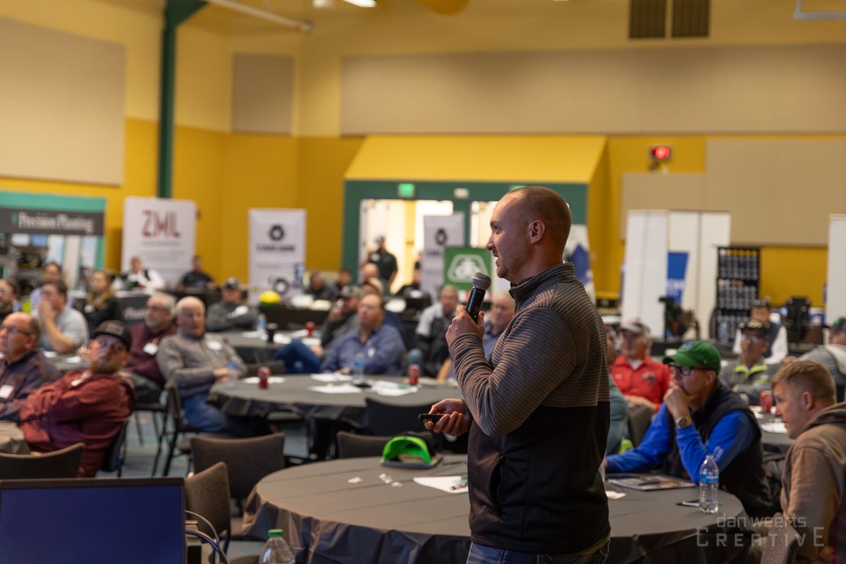 A man is standing in front of a crowd of people holding a microphone.