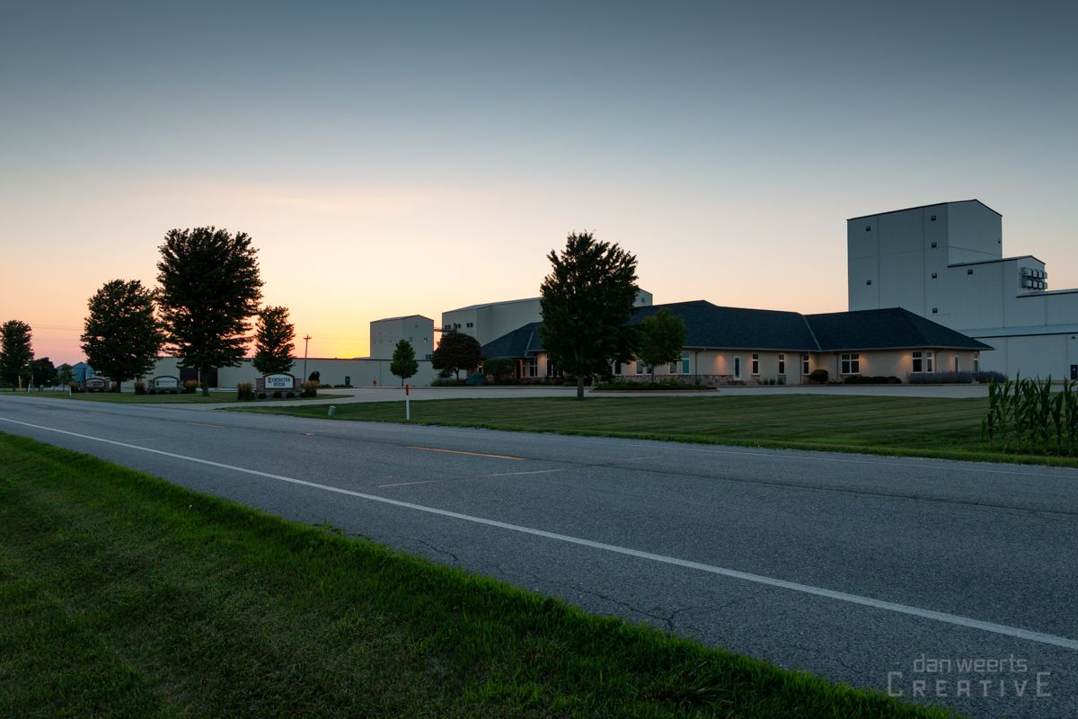 A sunset over a road with a building in the background