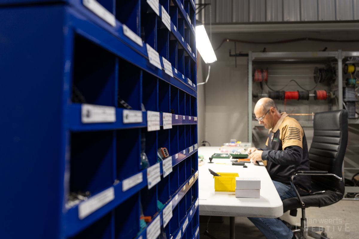 A man is sitting at a table in a factory working on a piece of equipment.