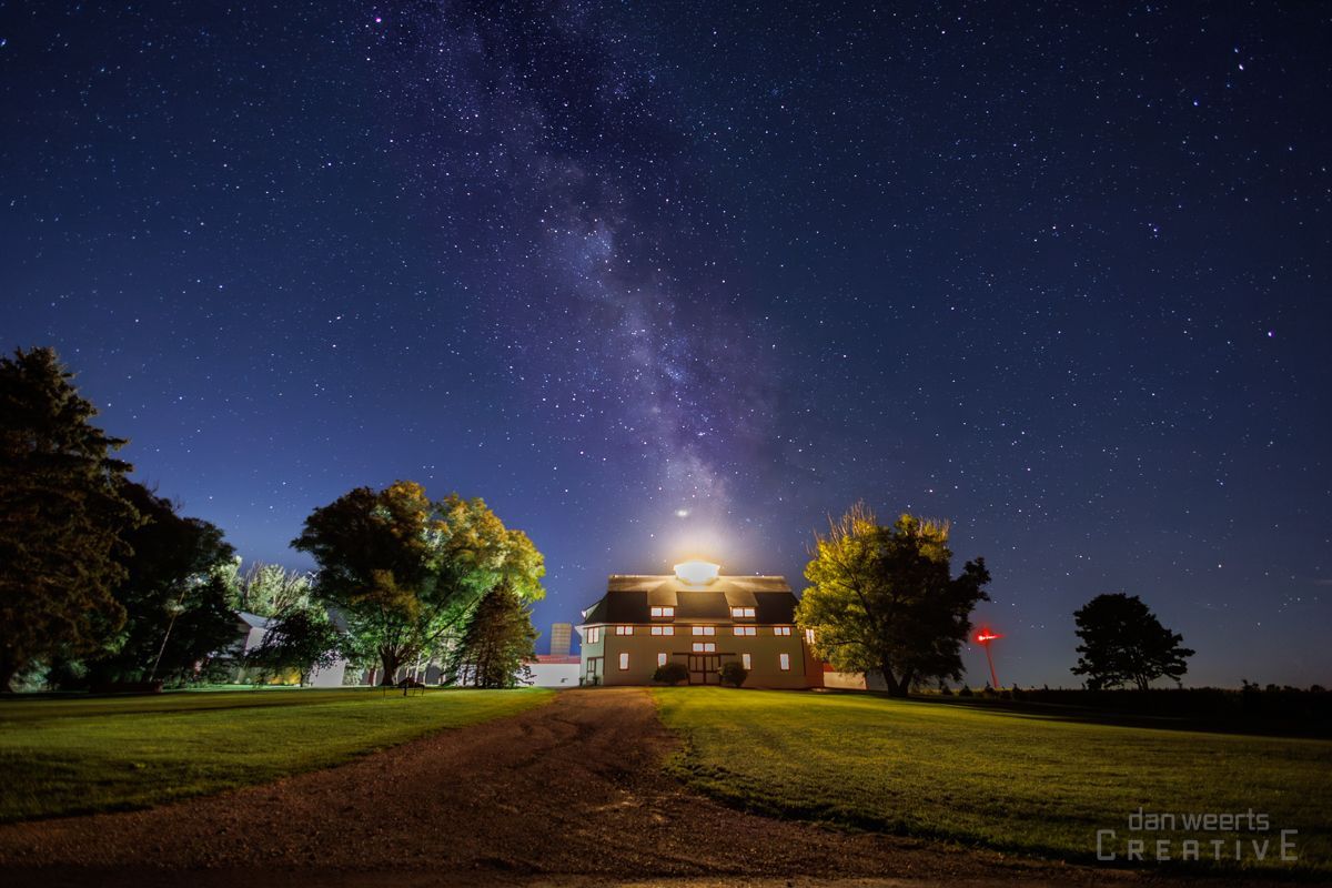 A house is lit up at night under a starry sky