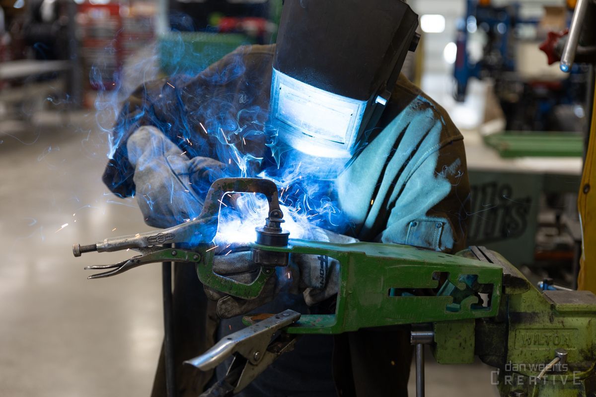 A man is welding a piece of metal in a factory.