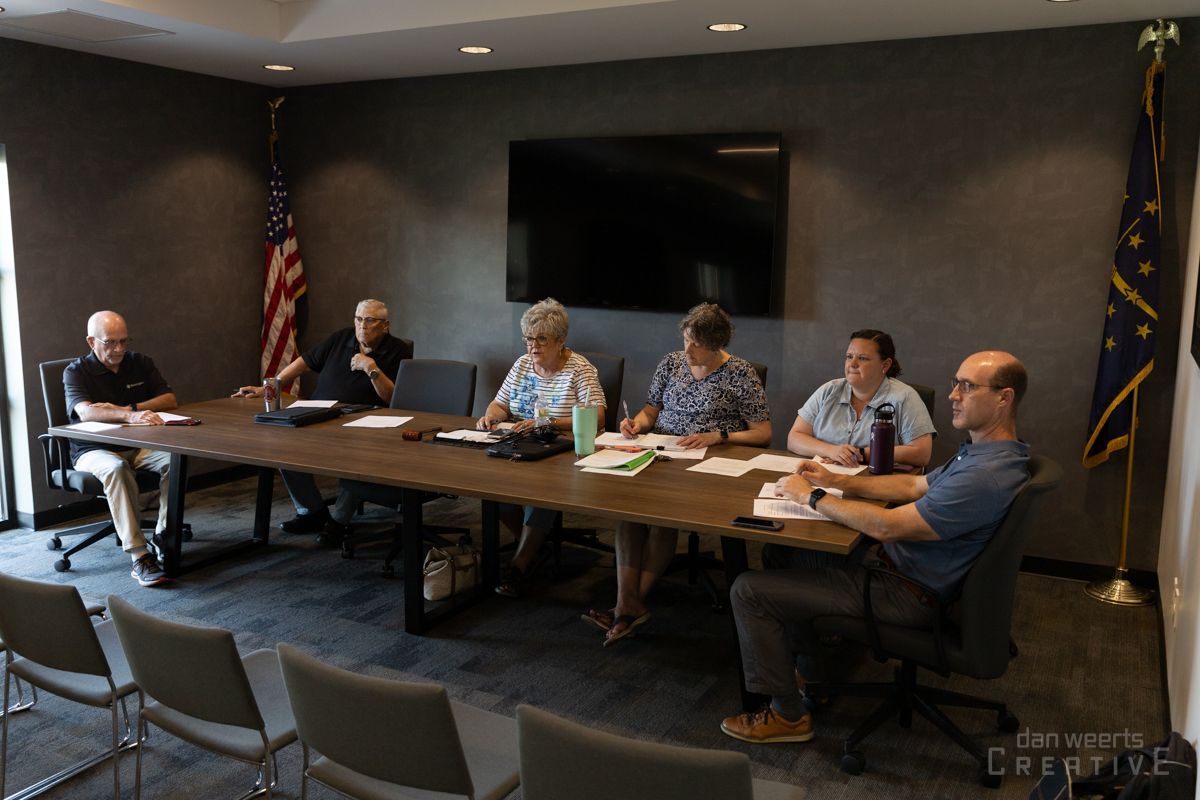 A group of people are sitting around a long table in a conference room.