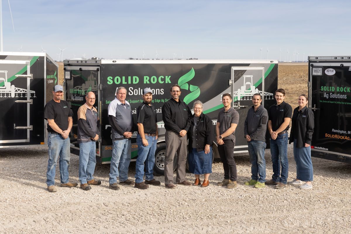 A group of people are posing for a picture in front of a trailer.