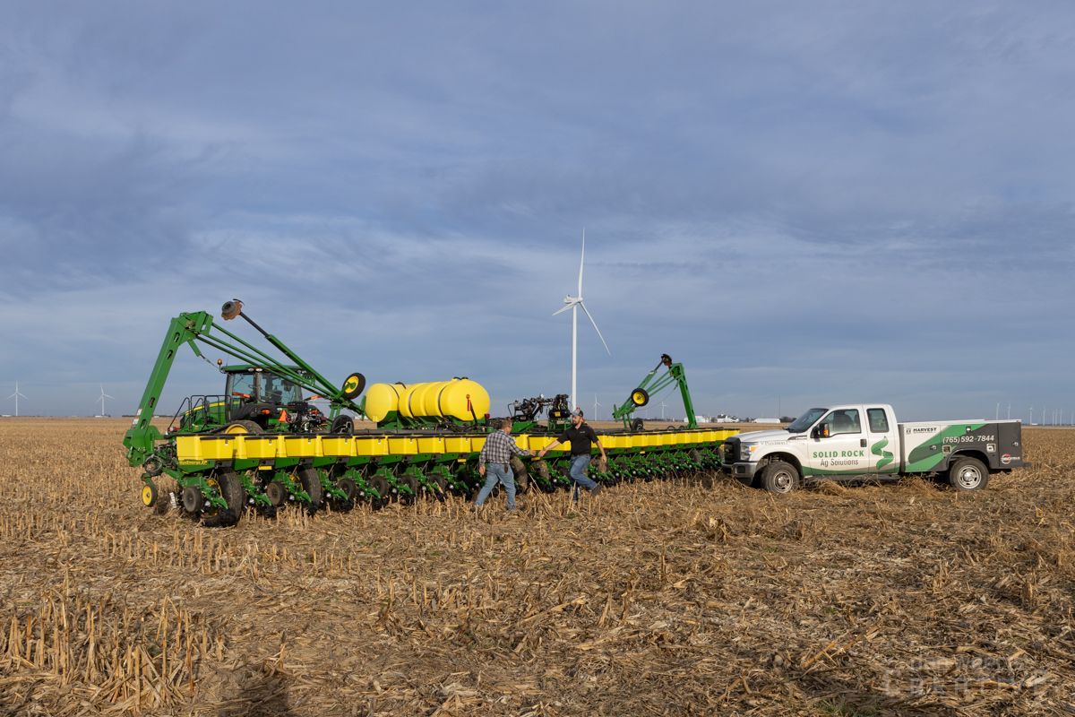 A group of people are working in a field with a tractor and a truck.
