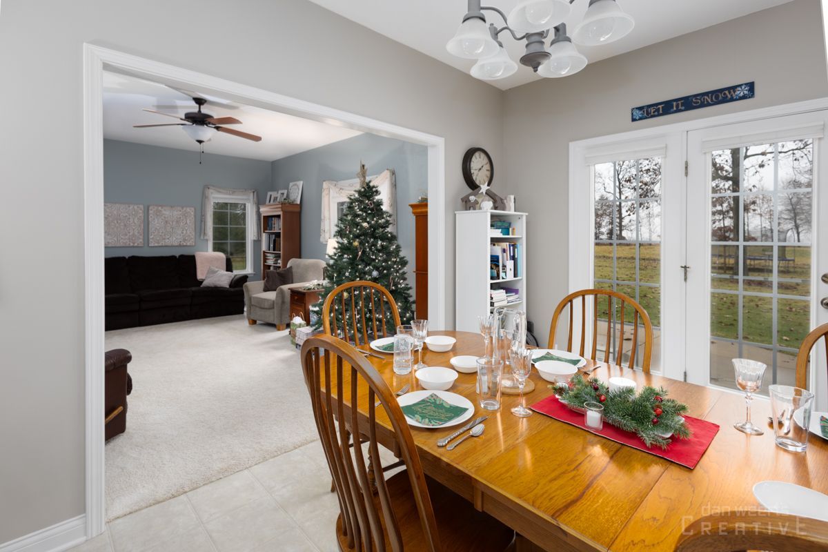 A dining room table and chairs in a house with a christmas tree in the background.