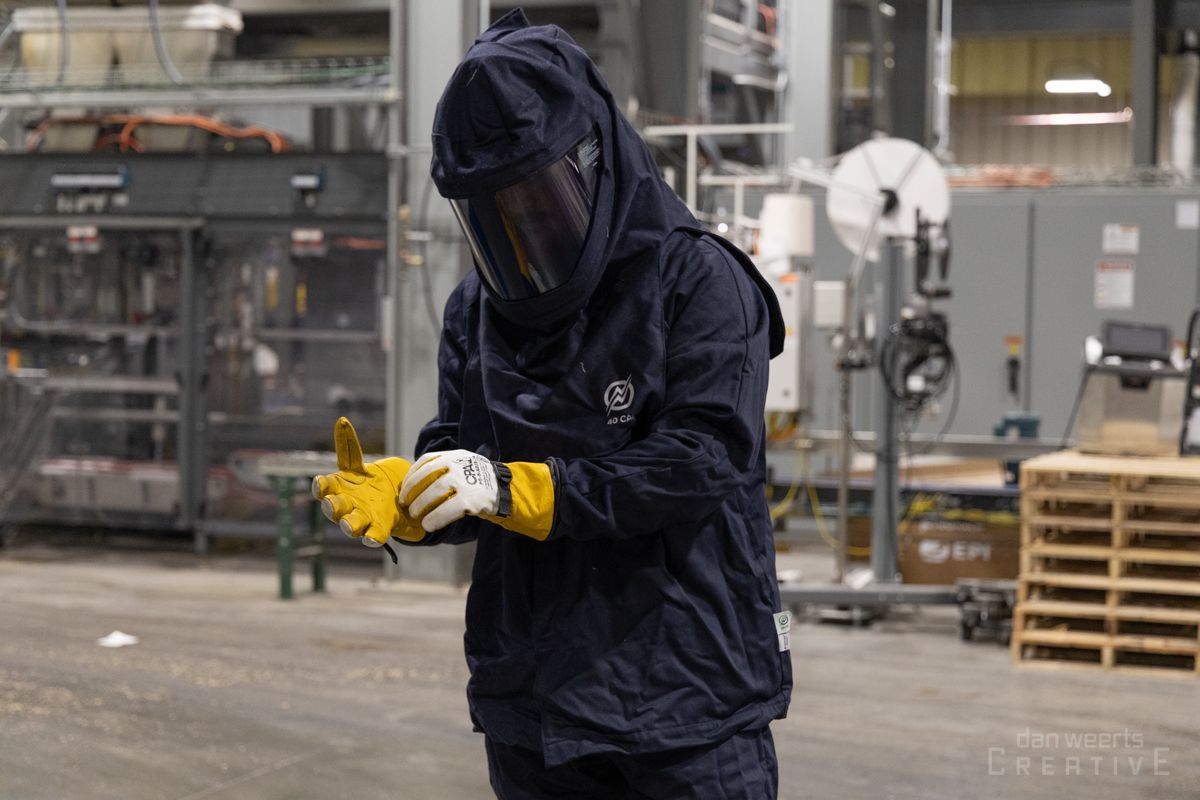 A man is wearing a protective suit and gloves in a factory.