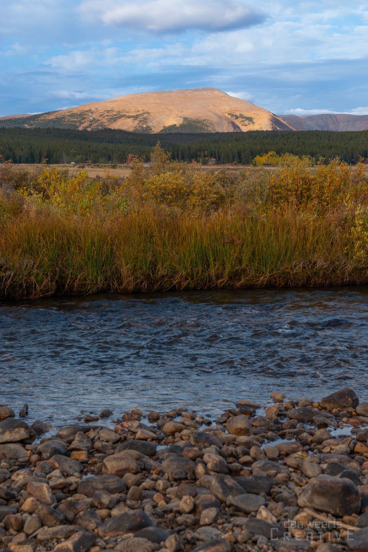 A river with a mountain in the background and rocks in the foreground.