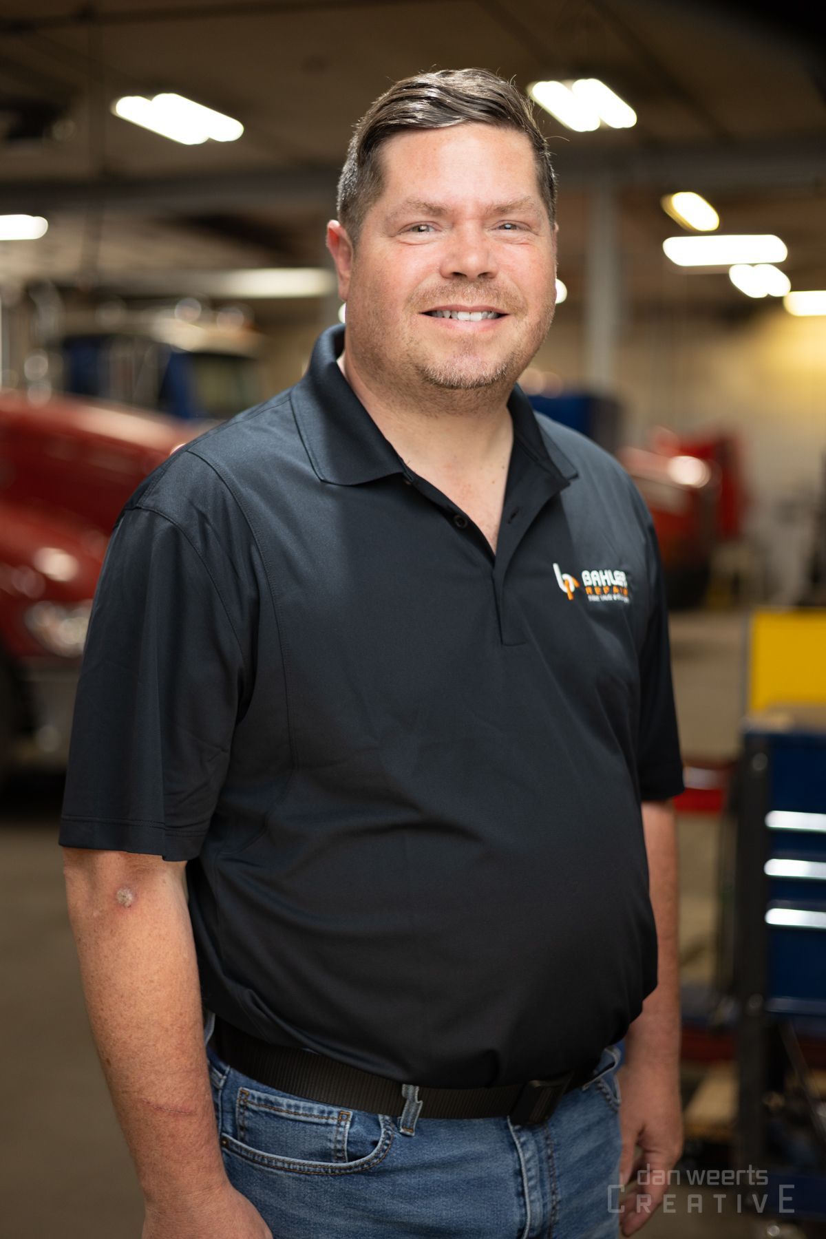 A man in a black shirt is standing in a garage.