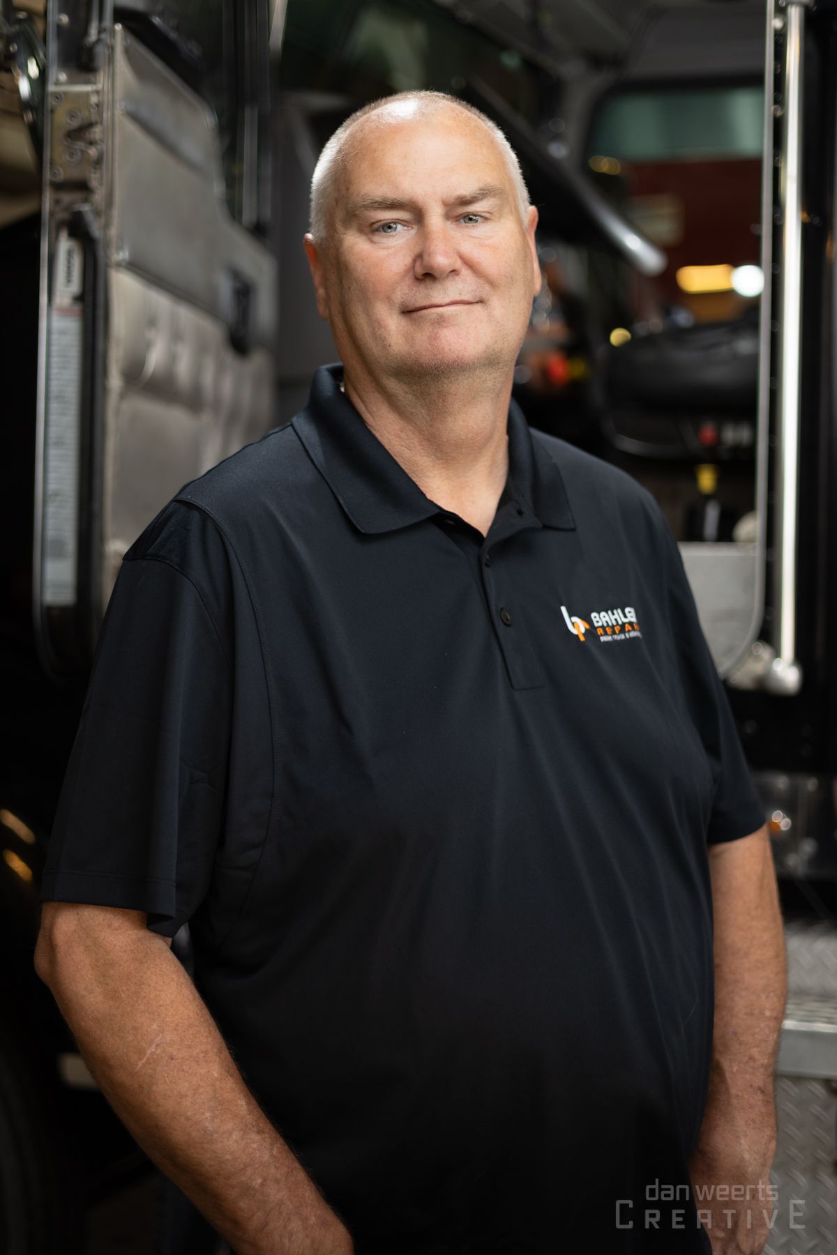 A man wearing a black shirt is standing in front of a truck.