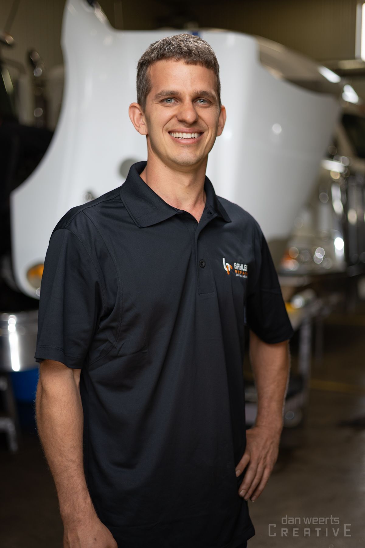 A man in a black shirt is standing in front of a white truck.