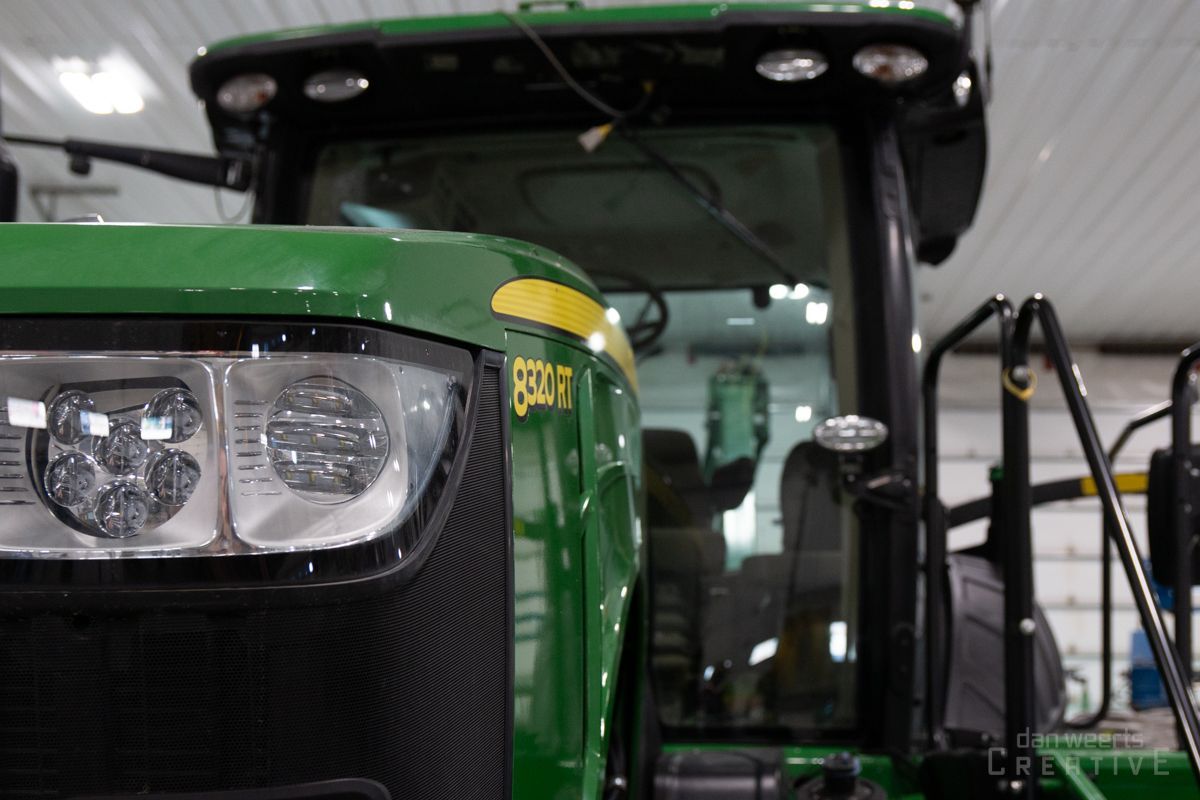 A green john deere tractor is parked in a garage.