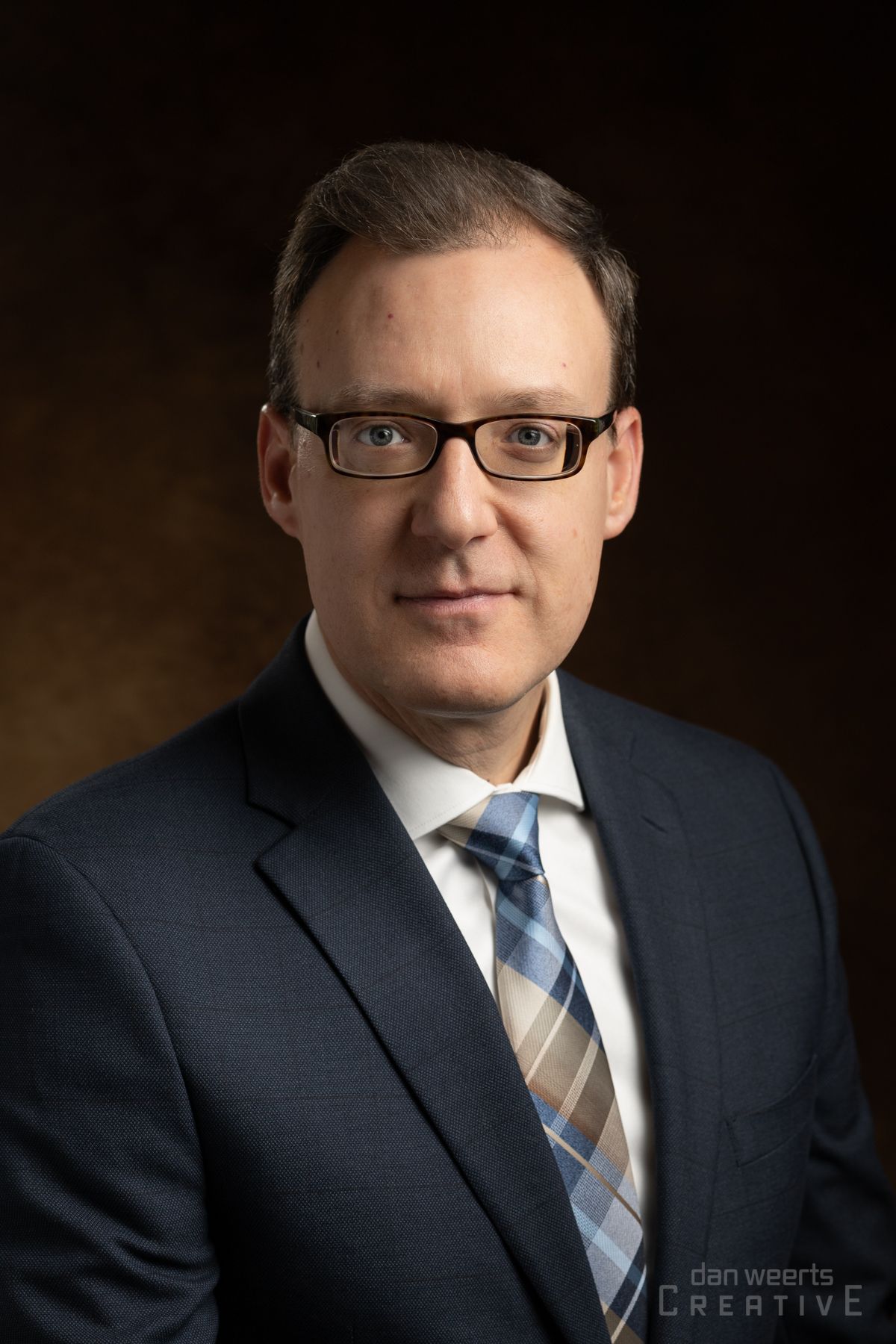 A man in a suit and tie is wearing glasses.