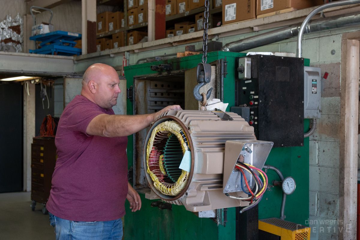 A man is working on an electric motor in a factory.