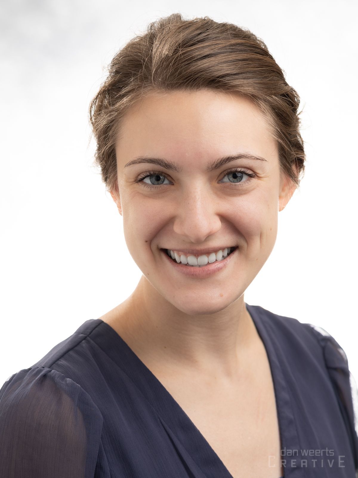 A man with a beard is smiling for the camera while wearing a black polo shirt.