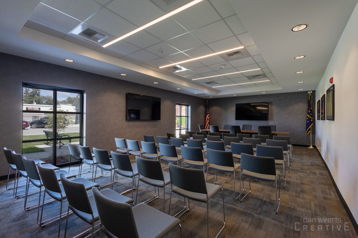A large room with rows of chairs and a television on the wall.