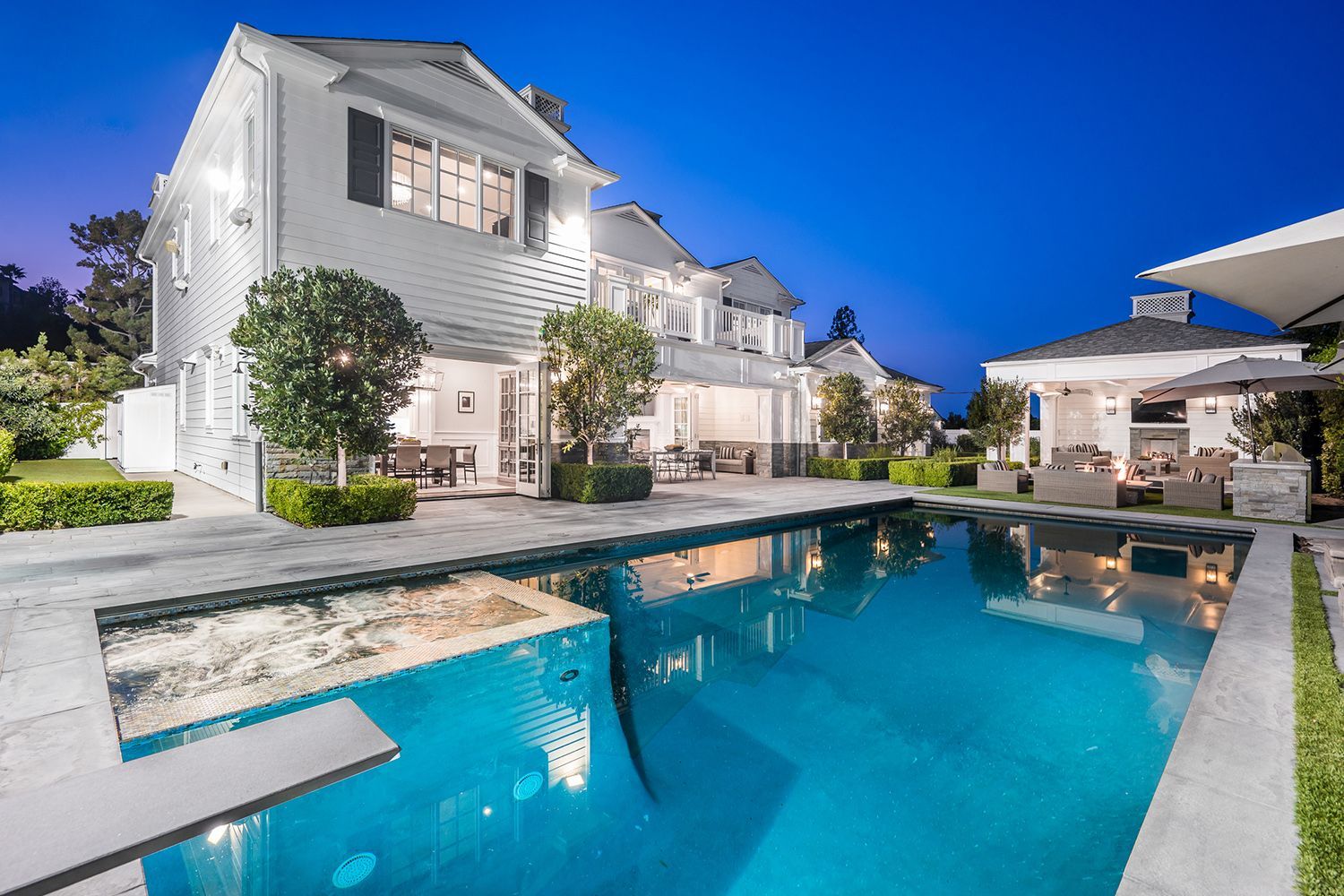 A large white house with a large swimming pool in front of it.