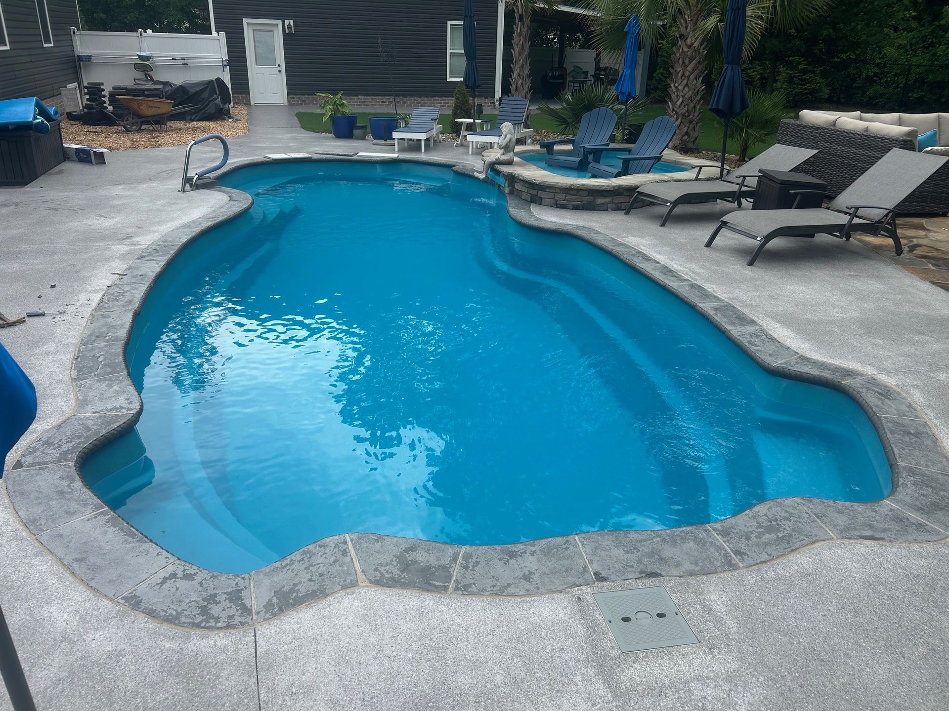 A large blue swimming pool surrounded by chairs and umbrellas