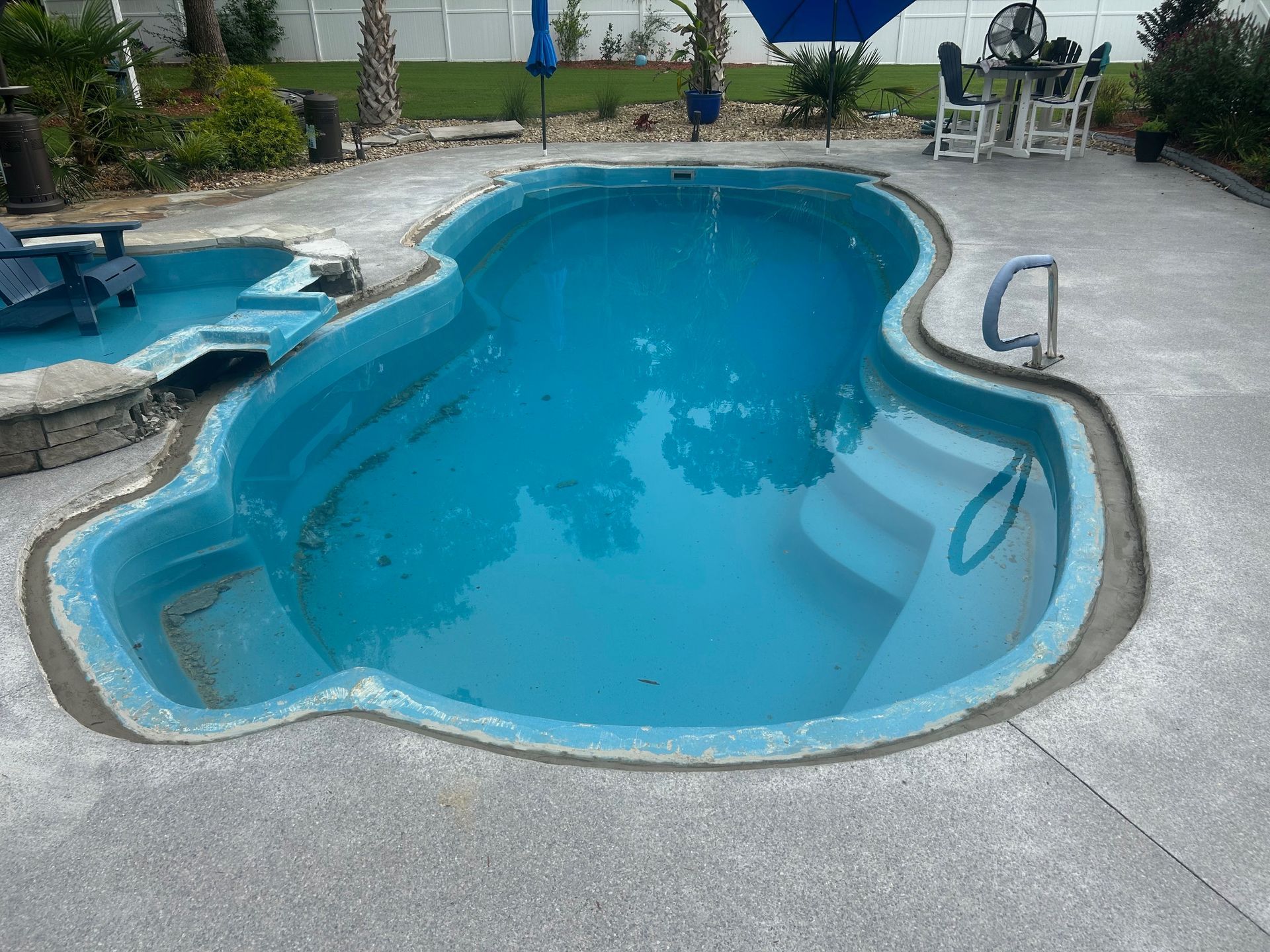 A large swimming pool with a blue umbrella in the background
