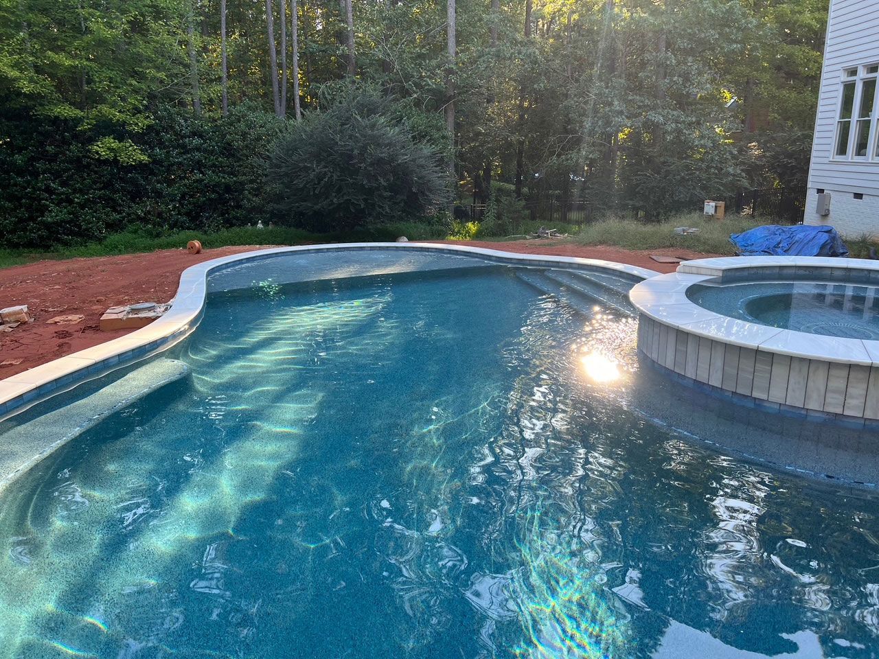 A large swimming pool with a hot tub in the middle of it.