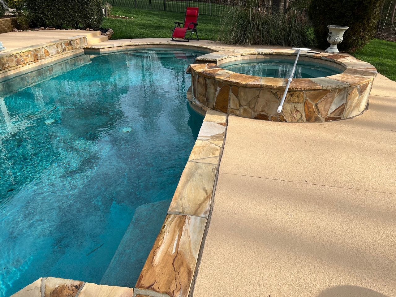 A large swimming pool with a hot tub next to it.
