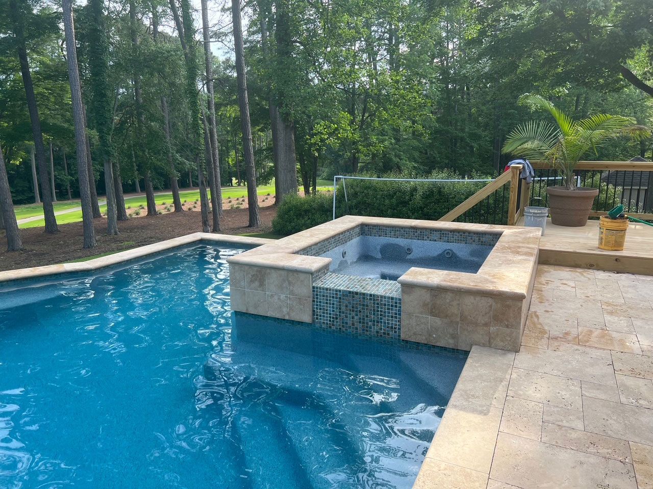 A large swimming pool with a hot tub in the middle of it