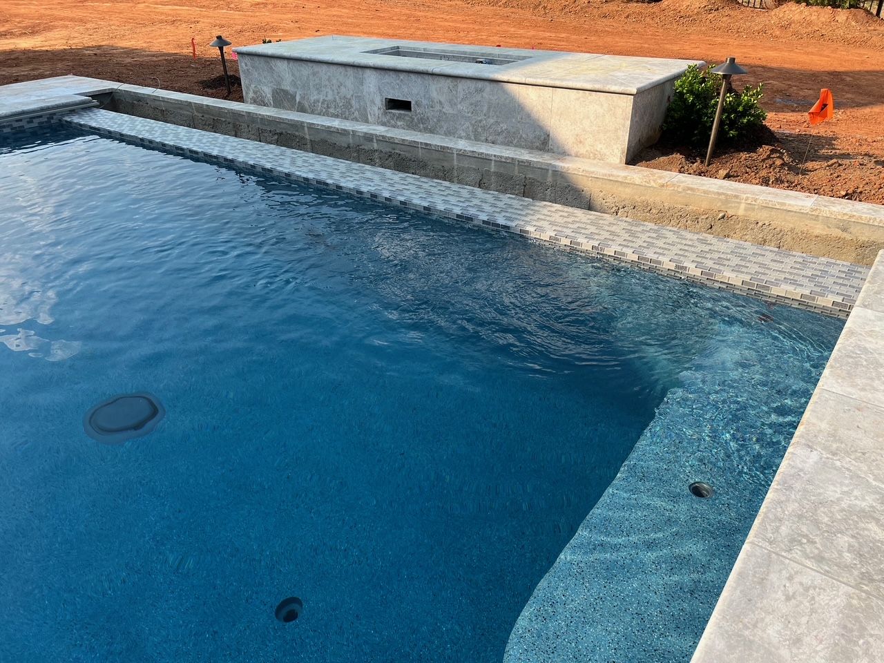 A large swimming pool with a hot tub in the background.