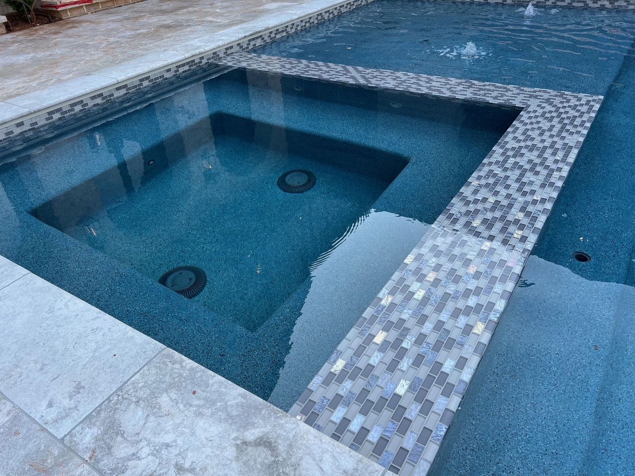 A swimming pool with a hot tub in the middle of it