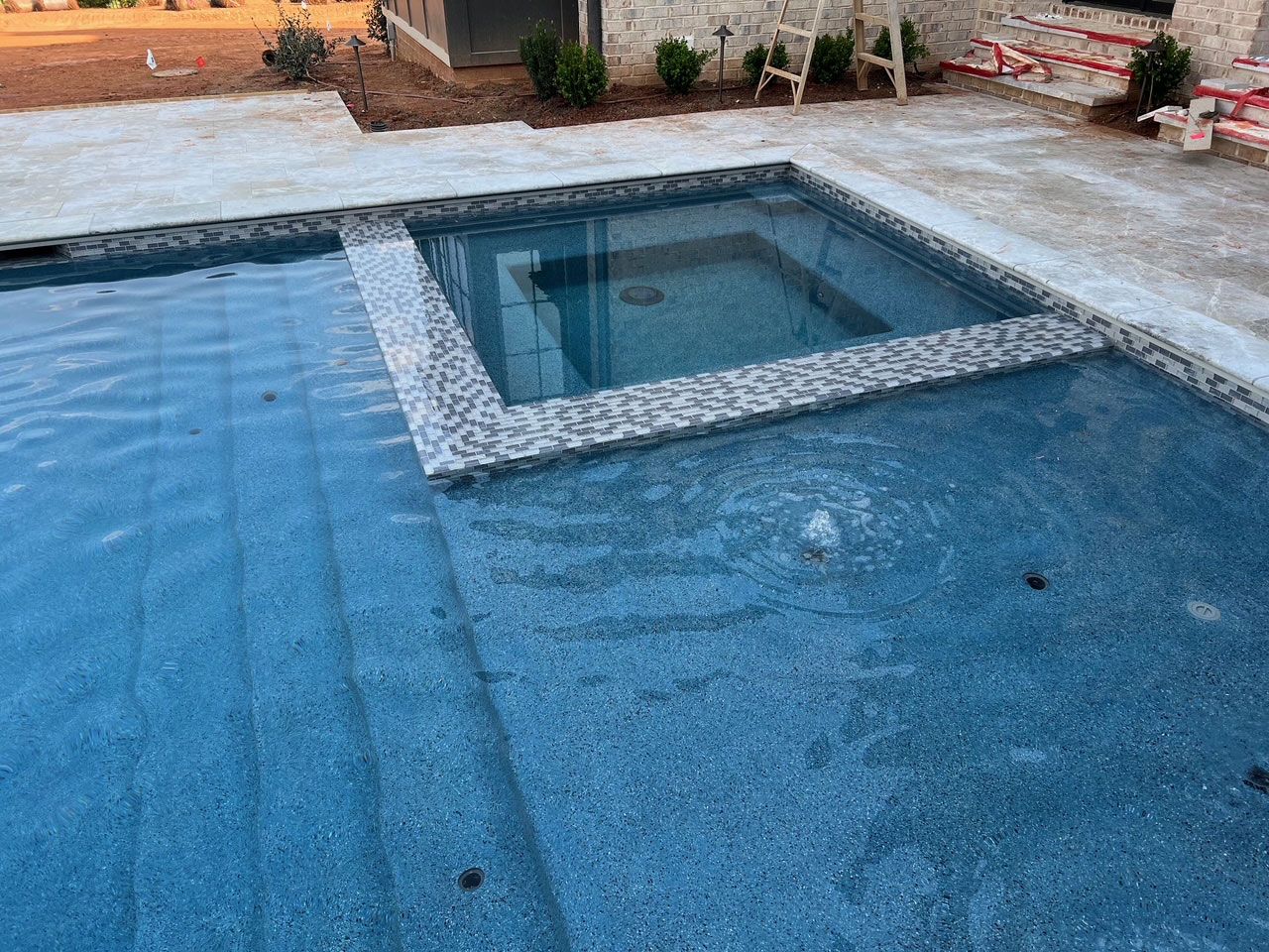 A large swimming pool with a hot tub in the middle of it.