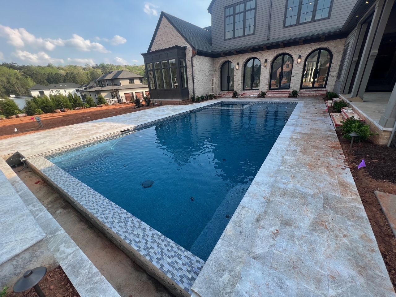 A large swimming pool is in front of a large house.