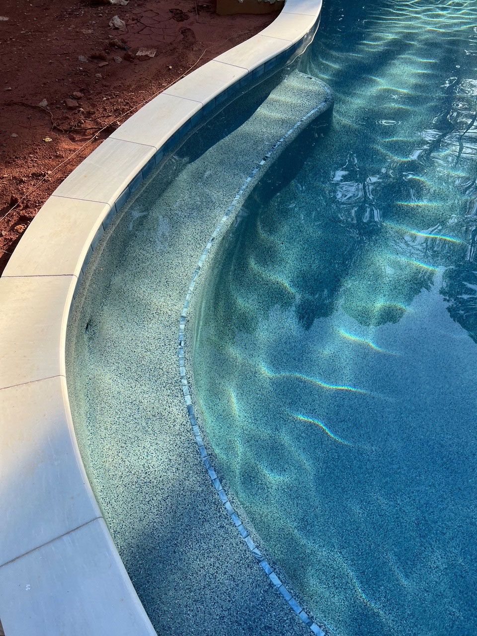 A close up of a curved edge of a swimming pool.