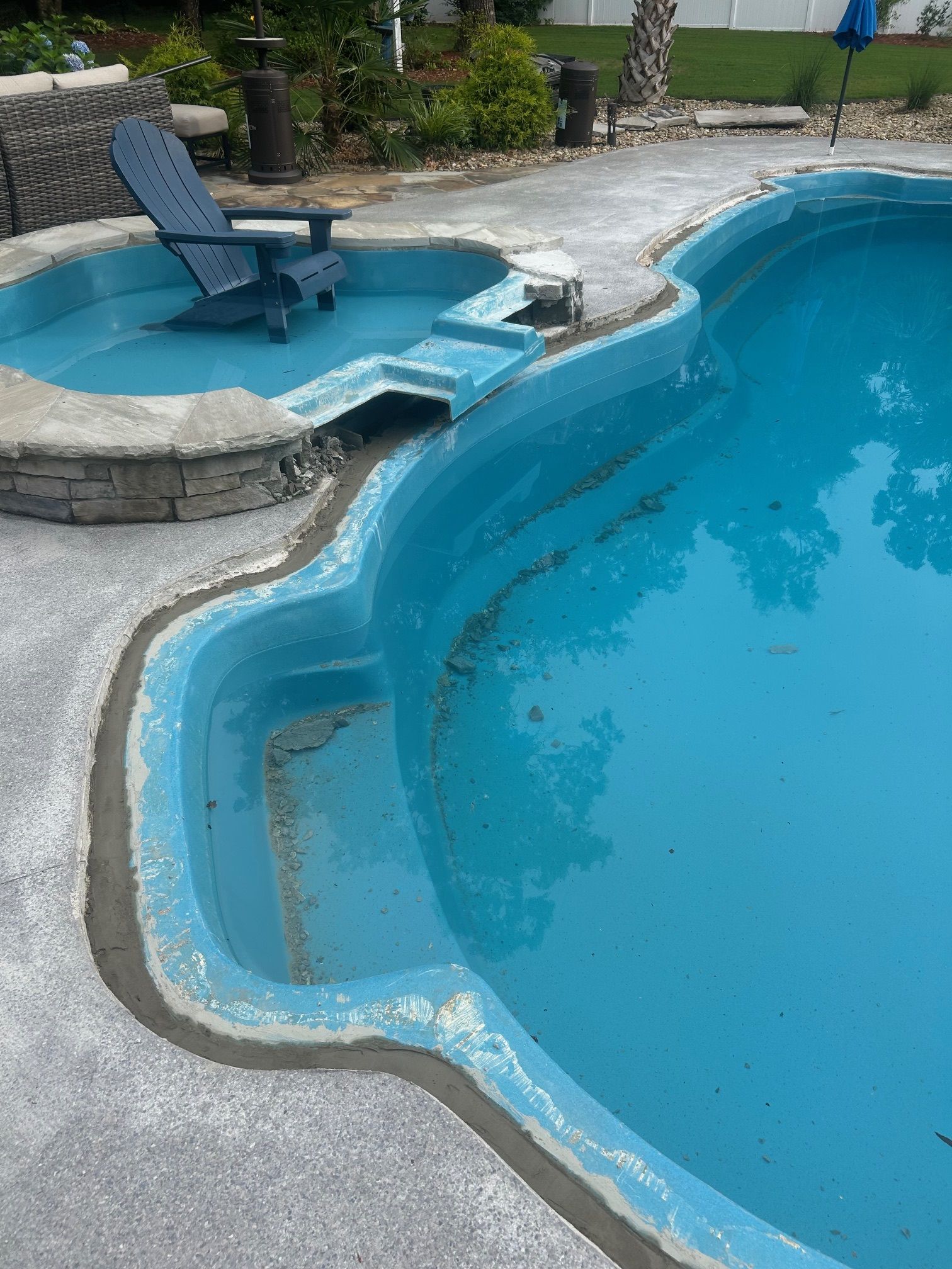 A swimming pool with a chair and umbrella in it.