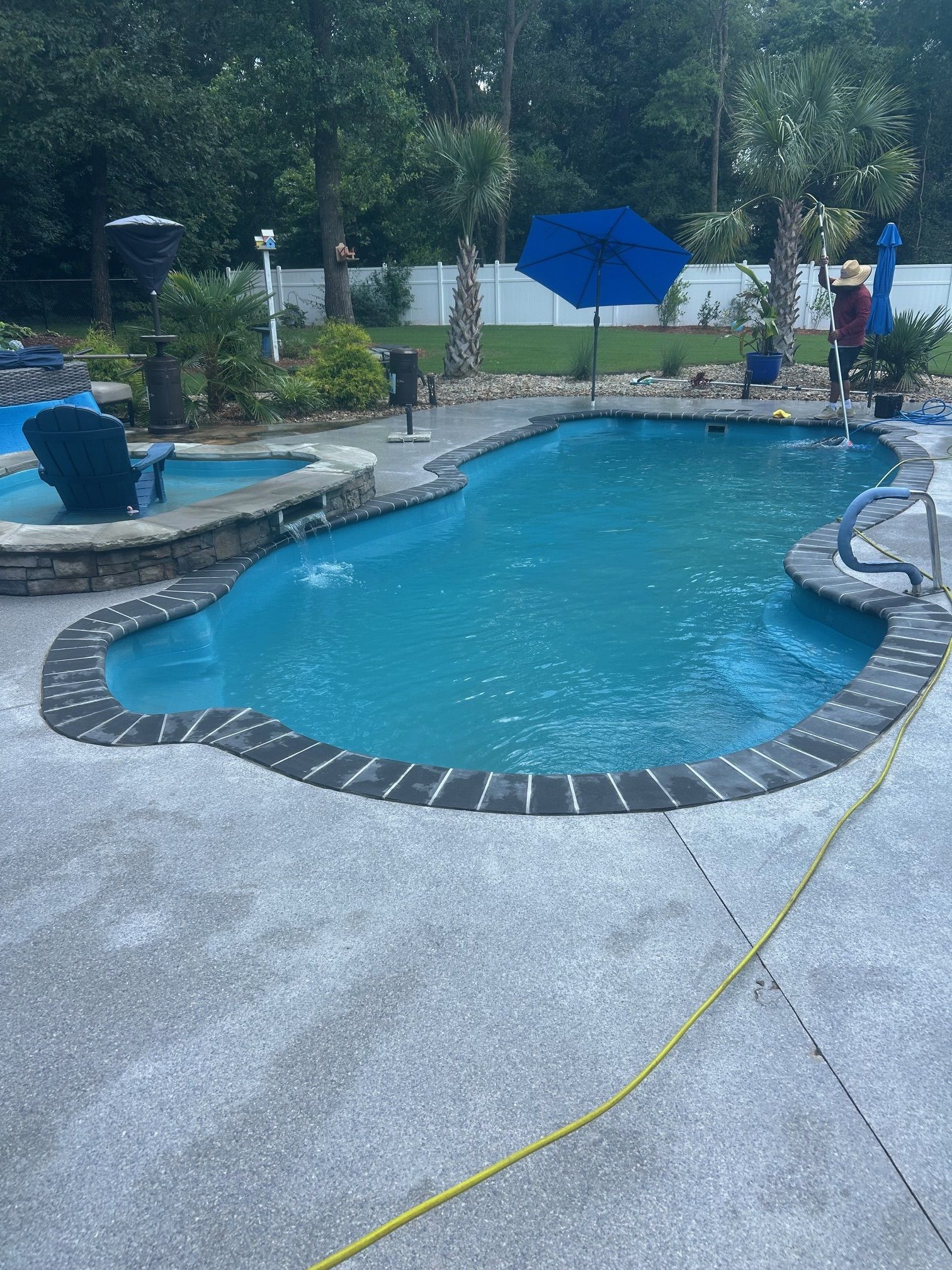A large swimming pool with a blue umbrella in the middle of it.