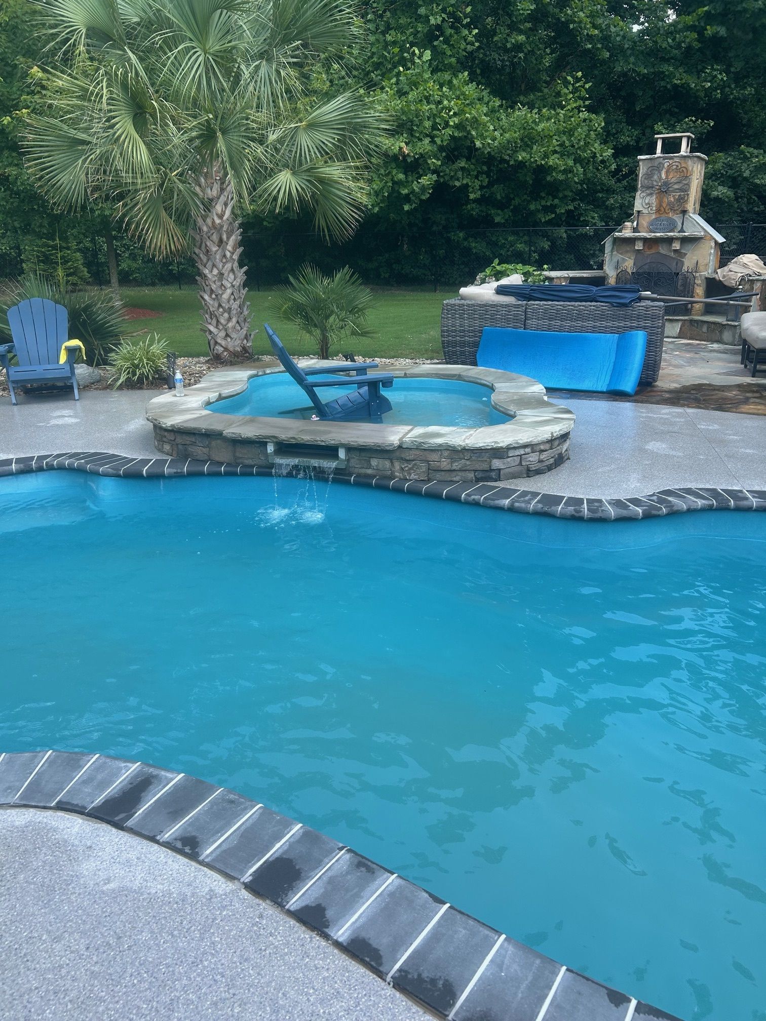 A large swimming pool with a hot tub in the backyard.
