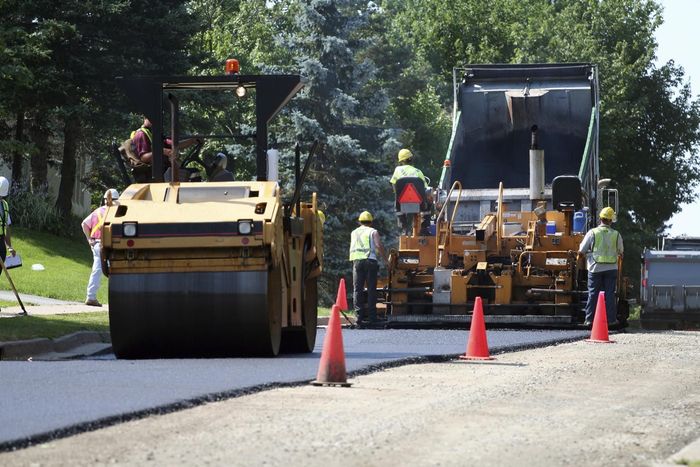 A group of construction workers are working on a road