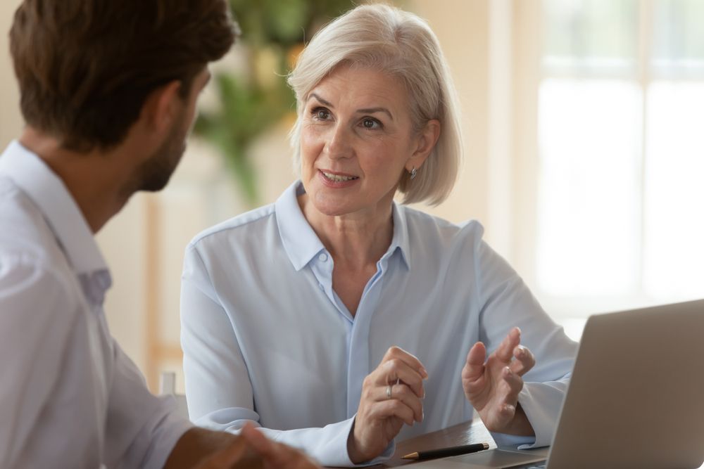 A man and a woman are sitting at a table with a laptop.