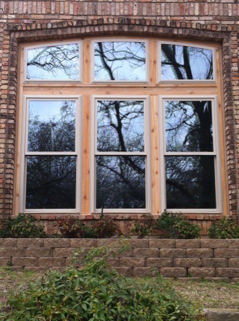 A large window on a brick building with trees reflected in it