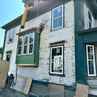 A house with a yellow hose attached to it and the letter h on the windows